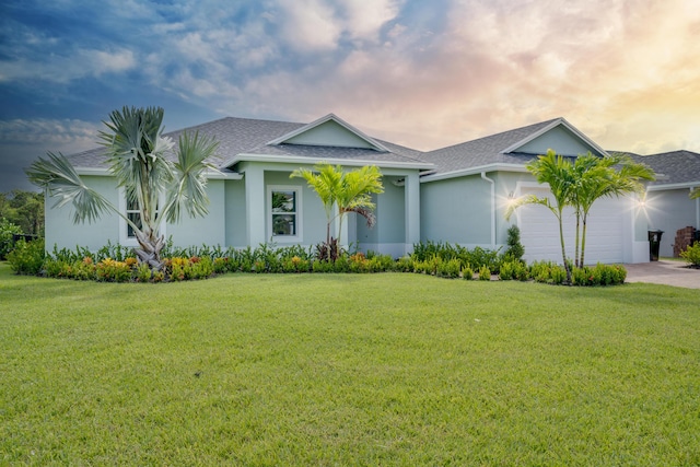 view of front facade featuring a front lawn, a shingled roof, stucco siding, and an attached garage