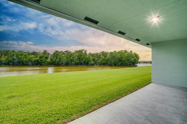 yard at dusk featuring visible vents and a water view
