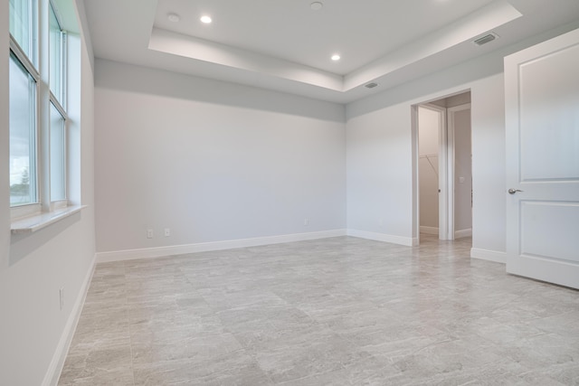empty room with baseboards, visible vents, recessed lighting, and a raised ceiling
