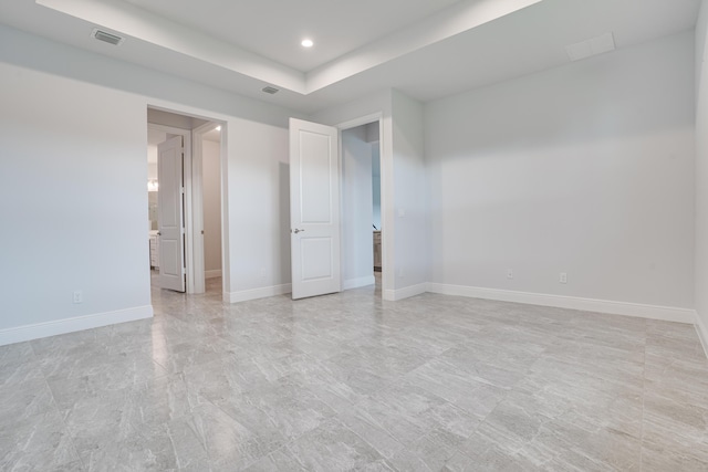 unfurnished bedroom with baseboards, a tray ceiling, visible vents, and recessed lighting