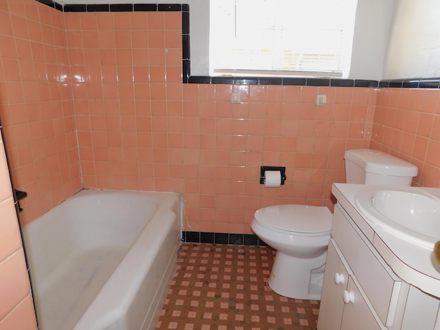 full bath with tile walls, a bath, vanity, and toilet
