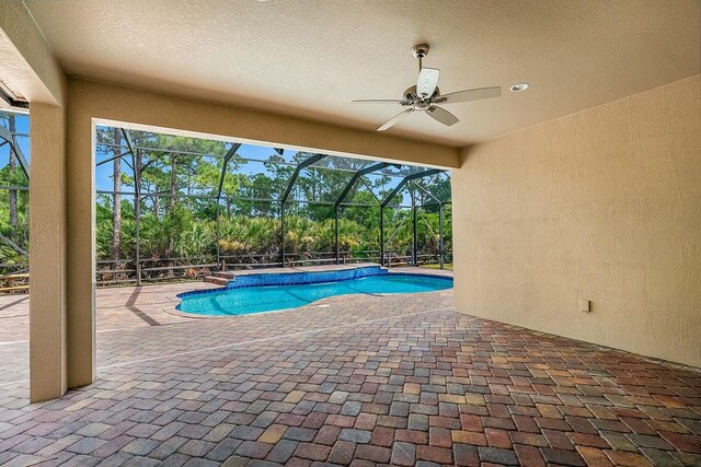 outdoor pool featuring a patio area, ceiling fan, and glass enclosure