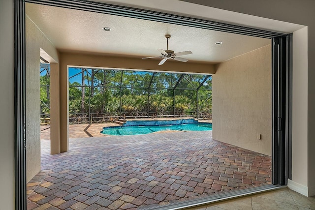 view of pool with a fenced in pool, a patio, glass enclosure, and ceiling fan