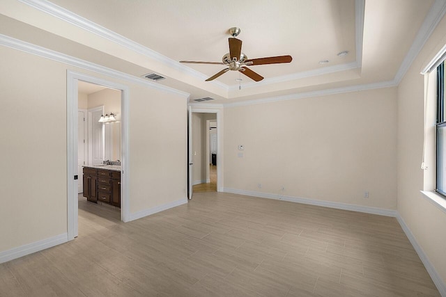 spare room featuring visible vents, a ceiling fan, ornamental molding, and a raised ceiling