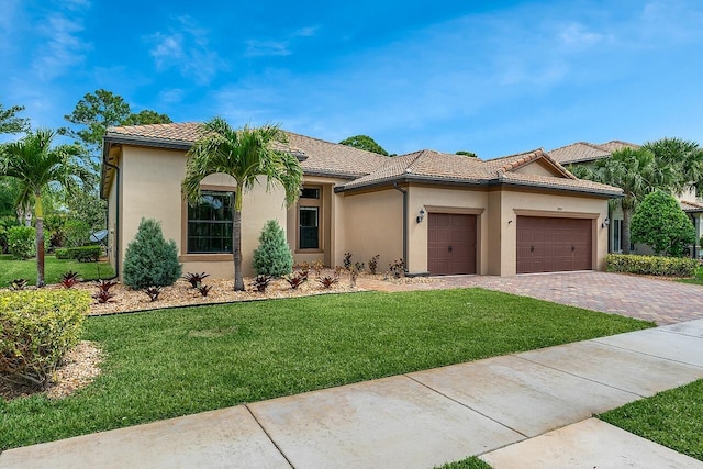 view of front facade with an attached garage, a tile roof, stucco siding, a front lawn, and driveway