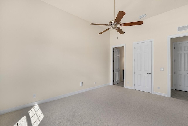 unfurnished bedroom featuring visible vents, baseboards, light colored carpet, and lofted ceiling