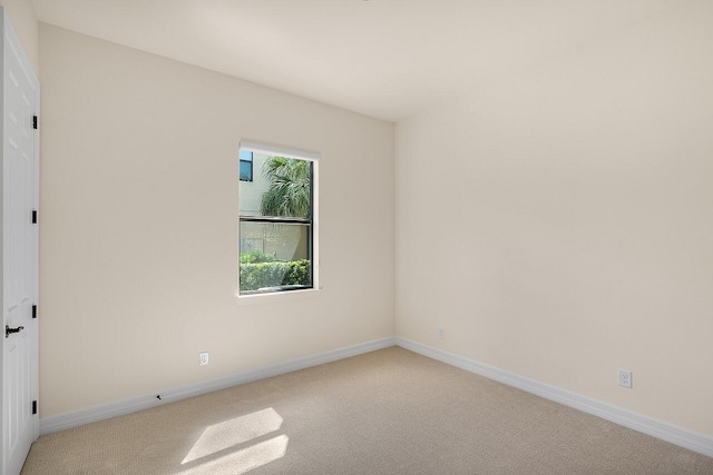 spare room with light carpet and baseboards