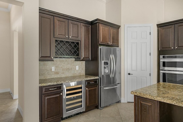 kitchen featuring light tile patterned floors, ornamental molding, stainless steel appliances, wine cooler, and baseboards