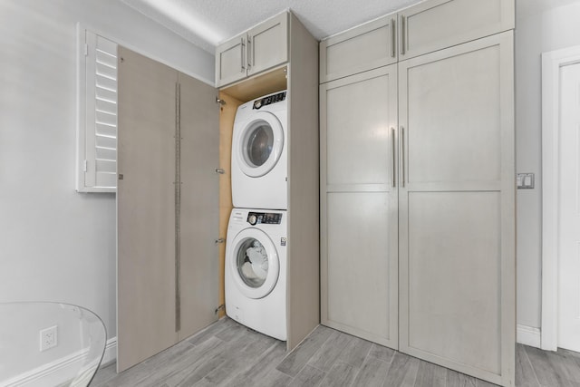 334 NW 42nd St, Boca Raton, FL 33431 - clothes washing area featuring cabinet space, stacked washer / dryer, and light wood-style flooring
