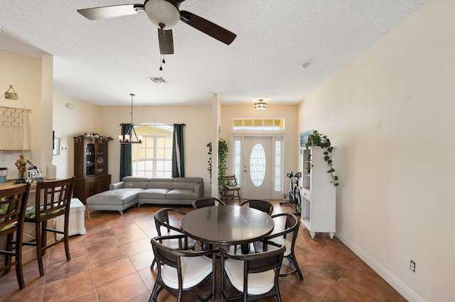 dining room featuring tile patterned floors, a textured ceiling, baseboards, visible vents, and ceiling fan with notable chandelier