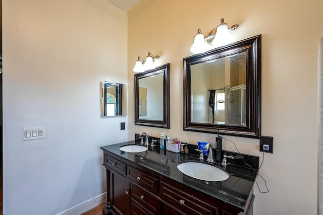 full bath with baseboards, a sink, and double vanity