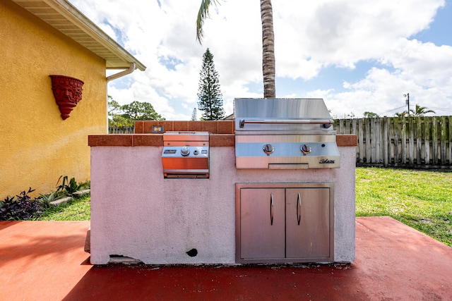 view of patio / terrace with grilling area, an outdoor kitchen, and fence