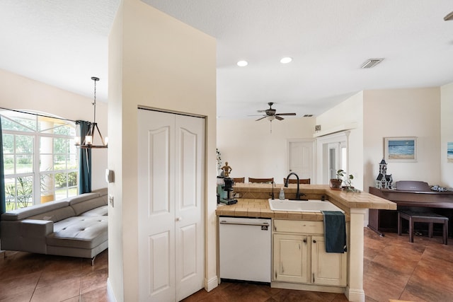 kitchen featuring white dishwasher, a sink, ceiling fan with notable chandelier, open floor plan, and cream cabinetry