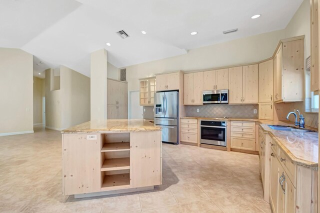 kitchen with visible vents, lofted ceiling, light brown cabinets, and open floor plan