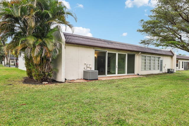 206 Lake Susan Ln, West Palm Beach, FL 33411 - rear view of property featuring stucco siding, a lawn, and central AC