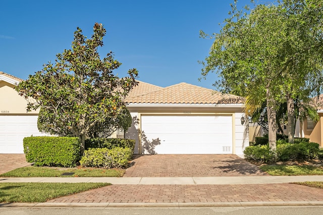 10828 SW Dardanelle Dr, Port Saint Lucie, FL 34987 - view of front of house with decorative driveway, a garage, stucco siding, and a tile roof