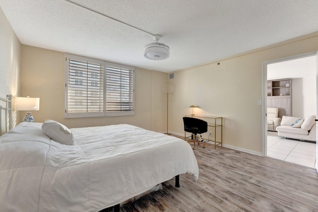 bedroom with visible vents, wood finished floors, baseboards, and a textured ceiling