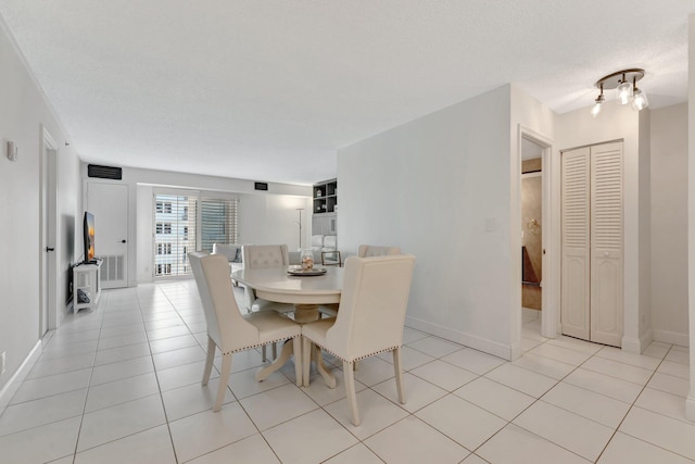 dining room with light tile patterned floors, baseboards, and a textured ceiling