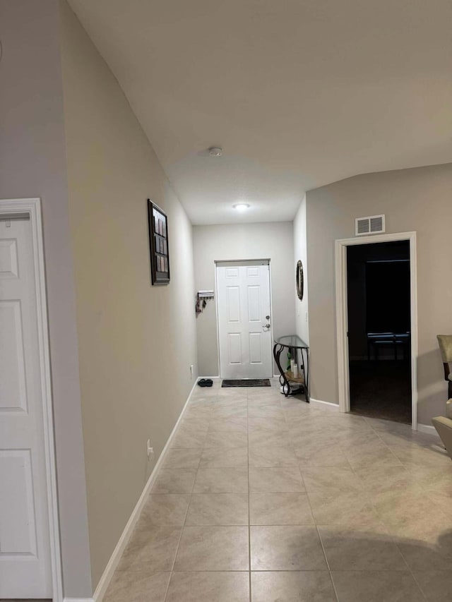 hallway featuring light tile patterned floors, visible vents, and baseboards