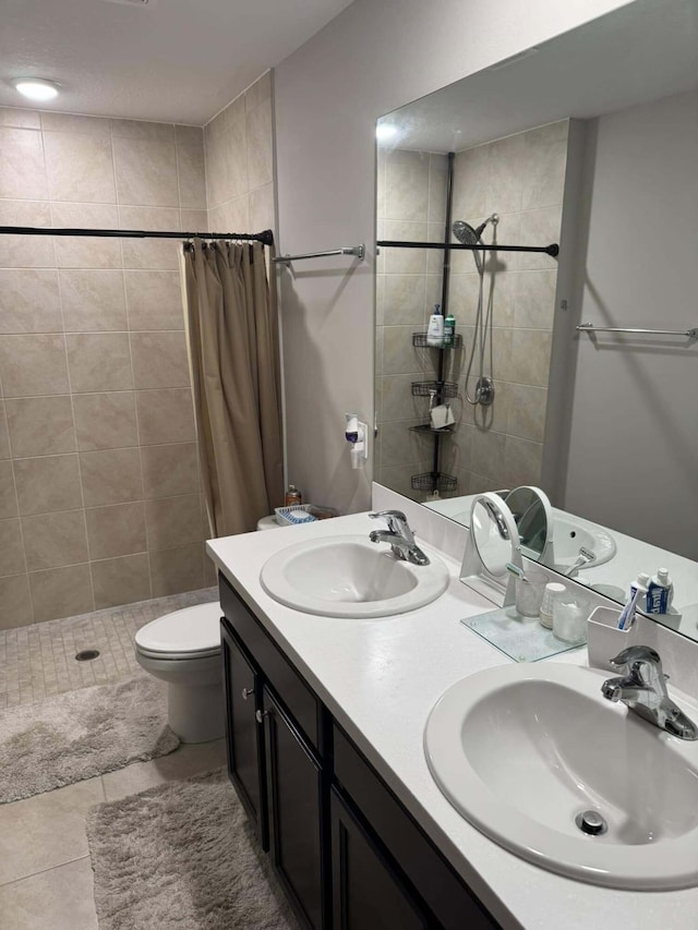 bathroom with tile patterned floors, tiled shower, and a sink