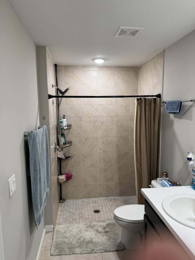 bathroom with a textured ceiling, vanity, visible vents, toilet, and a stall shower