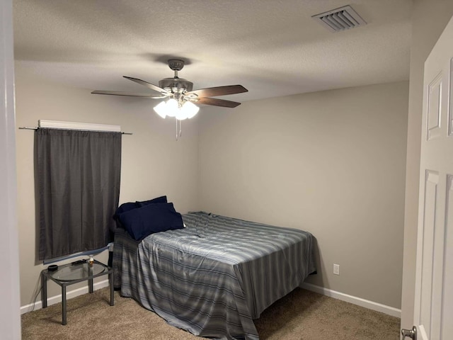 carpeted bedroom with visible vents, baseboards, ceiling fan, and a textured ceiling