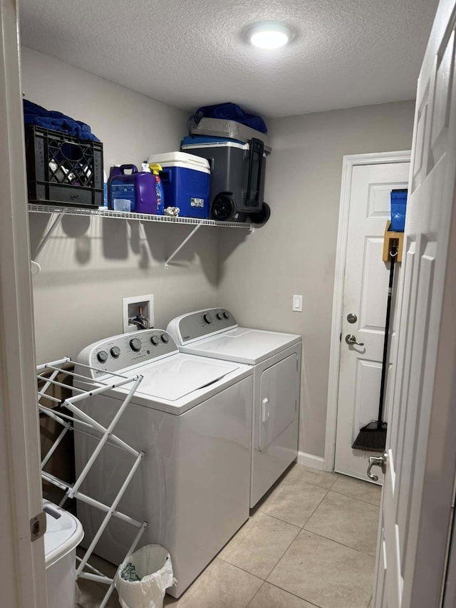laundry room with laundry area, independent washer and dryer, a textured ceiling, light tile patterned flooring, and baseboards