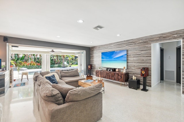 living area with recessed lighting, visible vents, light speckled floor, and an accent wall