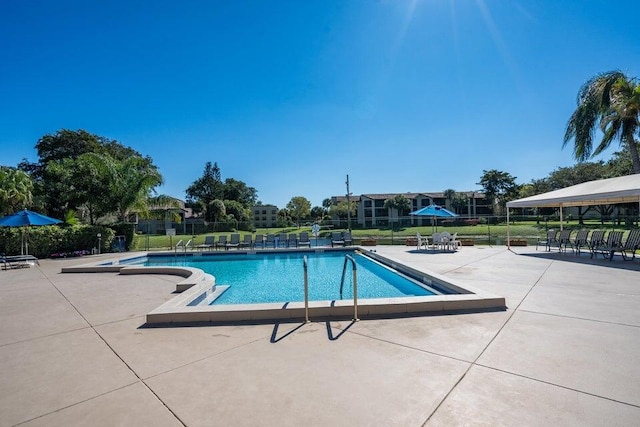 community pool with a patio area and fence