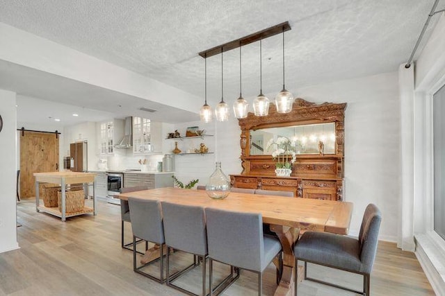 1000 N US Highway 1 Unit 656, Jupiter, FL 33477 - dining room featuring a barn door, light wood-style floors, and a textured ceiling