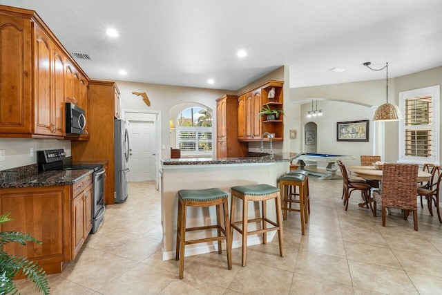 2999 Dovedale Ct, Wellington, FL 33414 - kitchen featuring open shelves, brown cabinets, stainless steel appliances, arched walkways, and dark stone counters