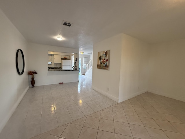 interior space with light tile patterned flooring, visible vents, and baseboards