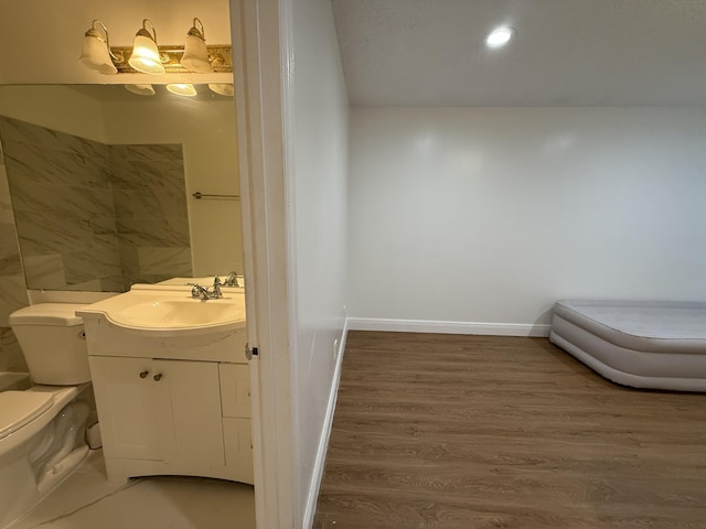 bathroom featuring wood finished floors, vanity, baseboards, toilet, and recessed lighting