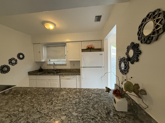 kitchen with white cabinets, dark stone countertops, visible vents, a sink, and white appliances