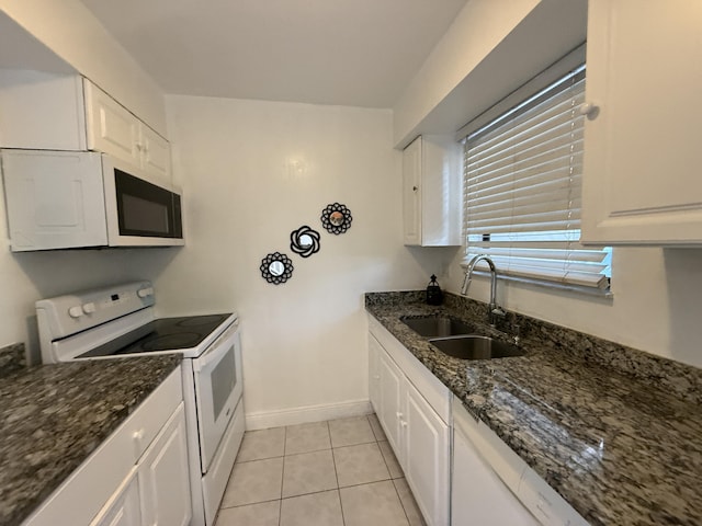 kitchen featuring white cabinetry, dark stone countertops, a sink, and white appliances