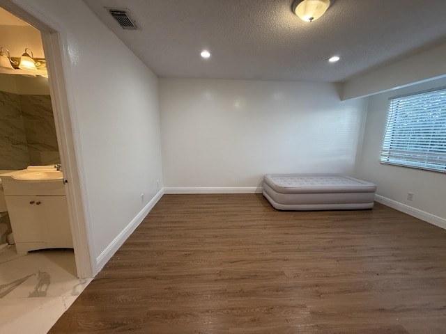 unfurnished bedroom featuring recessed lighting, wood finished floors, visible vents, and a sink