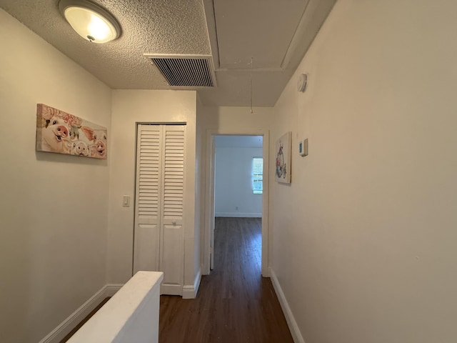 hall featuring attic access, baseboards, dark wood-style flooring, and visible vents