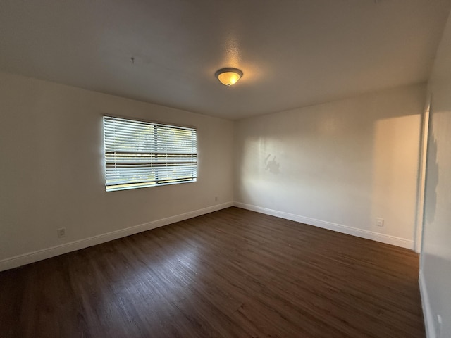 empty room with baseboards and dark wood-style floors