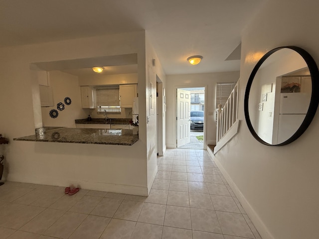 hallway featuring stairway, baseboards, a wealth of natural light, and light tile patterned floors