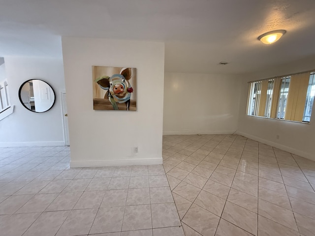 unfurnished room with baseboards and light tile patterned floors