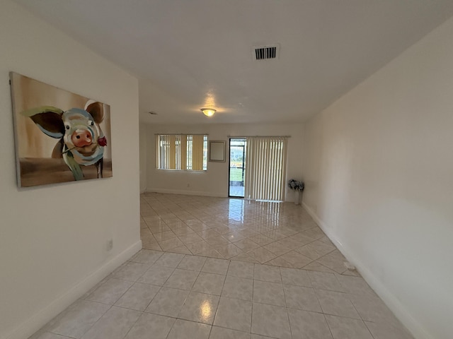 empty room featuring baseboards, visible vents, and light tile patterned floors