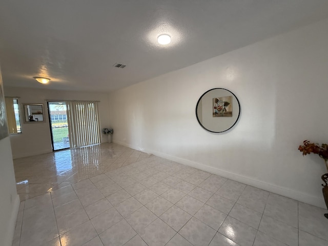 unfurnished room featuring baseboards, visible vents, and light tile patterned floors