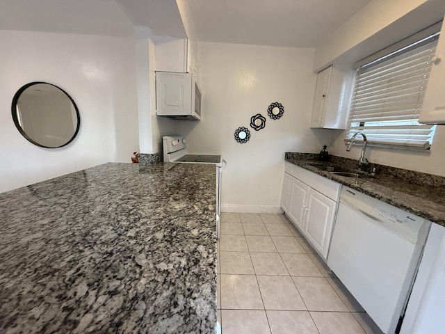 kitchen with dark stone counters, white cabinetry, a sink, and white appliances