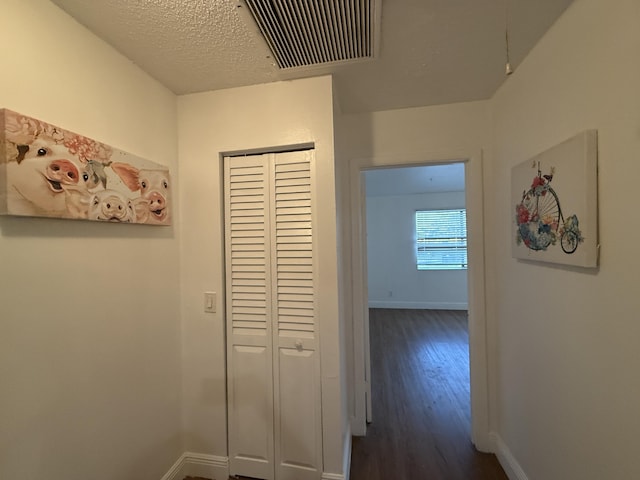 hallway with baseboards, dark wood-style flooring, and visible vents