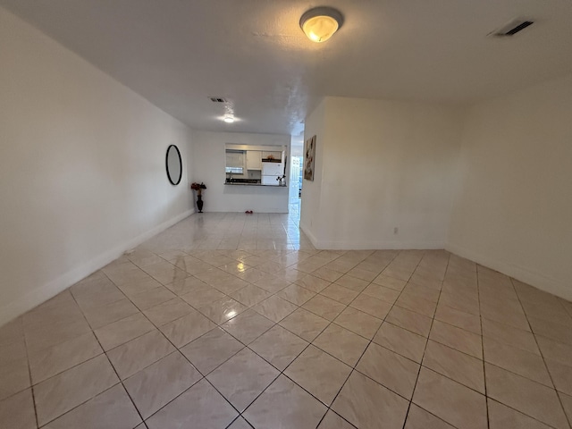 spare room with baseboards, light tile patterned flooring, and visible vents