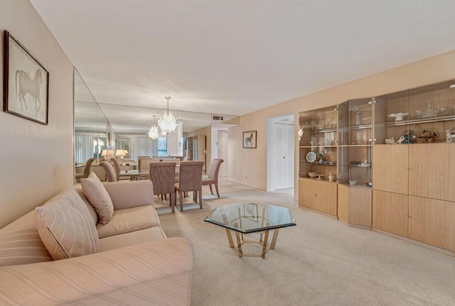 living area featuring visible vents, a notable chandelier, and light carpet