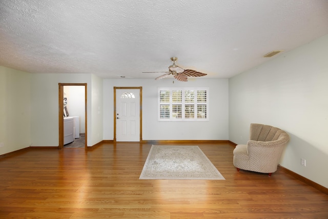 foyer entrance featuring a ceiling fan, a textured ceiling, light wood-style flooring, and visible vents