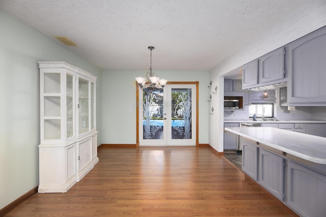 kitchen with gray cabinets, light countertops, dark wood finished floors, visible vents, and an inviting chandelier