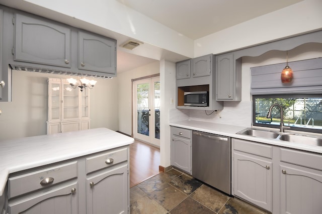 kitchen featuring light countertops, gray cabinets, stainless steel appliances, a sink, and stone finish flooring