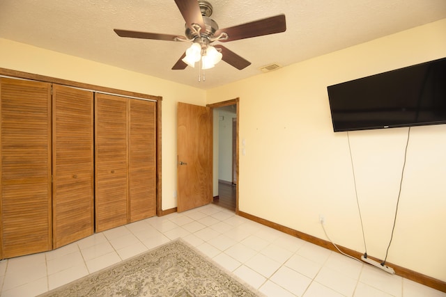unfurnished bedroom with light tile patterned floors, baseboards, a textured ceiling, visible vents, and a ceiling fan